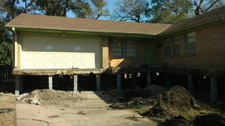 A house elevated on piers during a house raising project by Du-West, ensuring a stable foundation and protection against flooding.